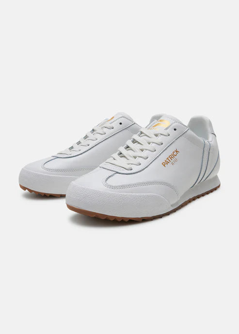 A pair of white Patrick Rio trainer shoes with a suede upper and a rubber sole, featuring a contrast striped panel and a gold foil logo.