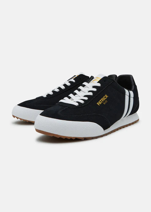 A black and white Patrick Rio trainer shoe with a suede upper and a rubber sole, featuring a contrast striped panel and a gold Patrick logo.