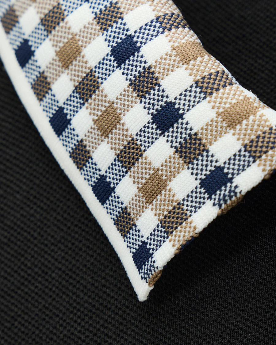 Close-up of a plaid fabric with brown, blue, and white pattern on a black background