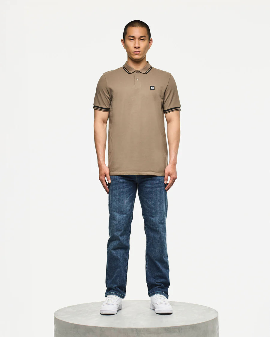 Man wearing a brown polo shirt and blue jeans on a white background