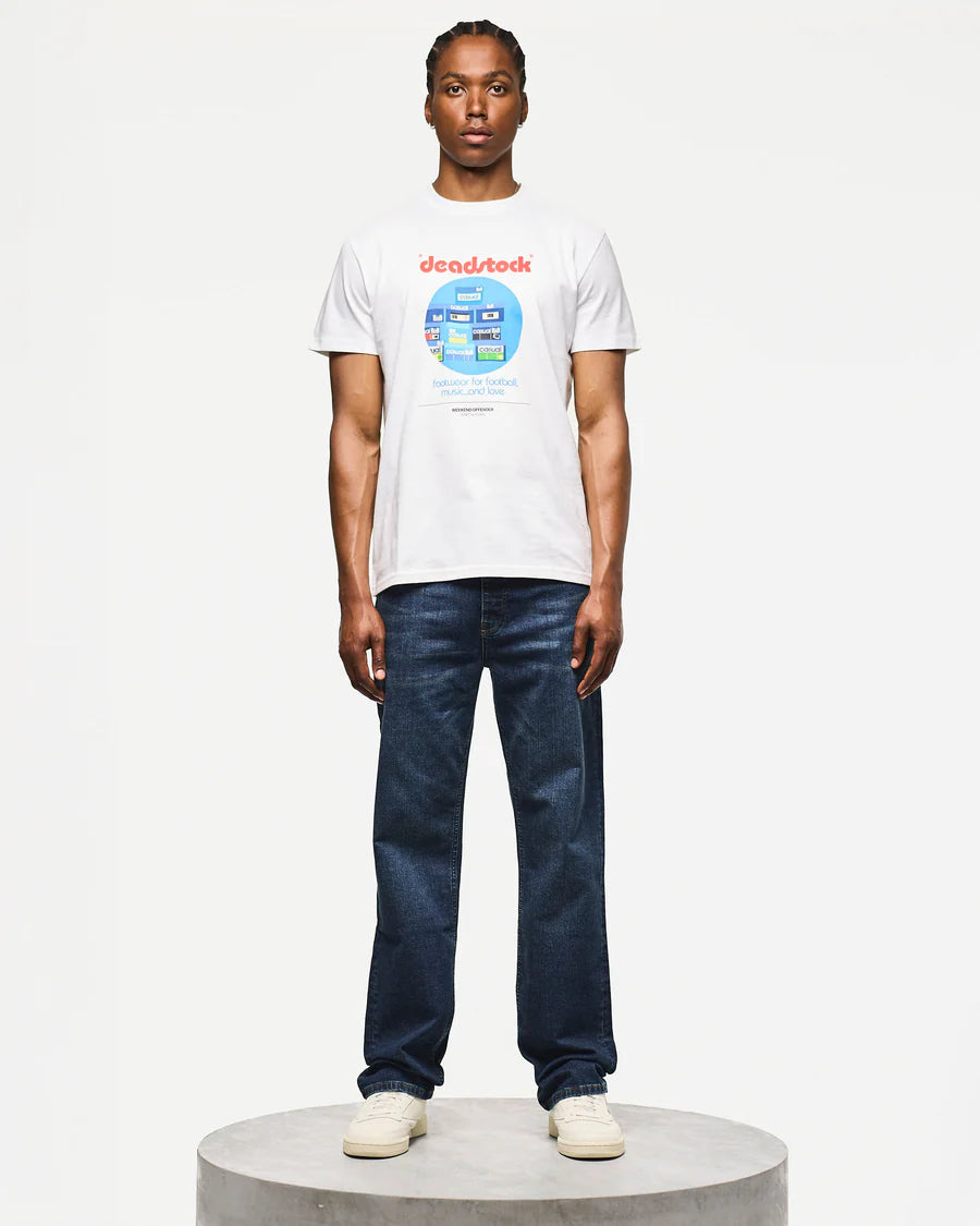 Person wearing a white t-shirt with a colorful graphic and dark blue jeans on a white background