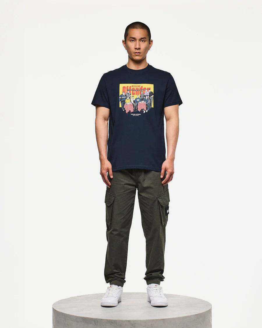 Person wearing a navy t-shirt with a colorful graphic and green cargo pants on a white background