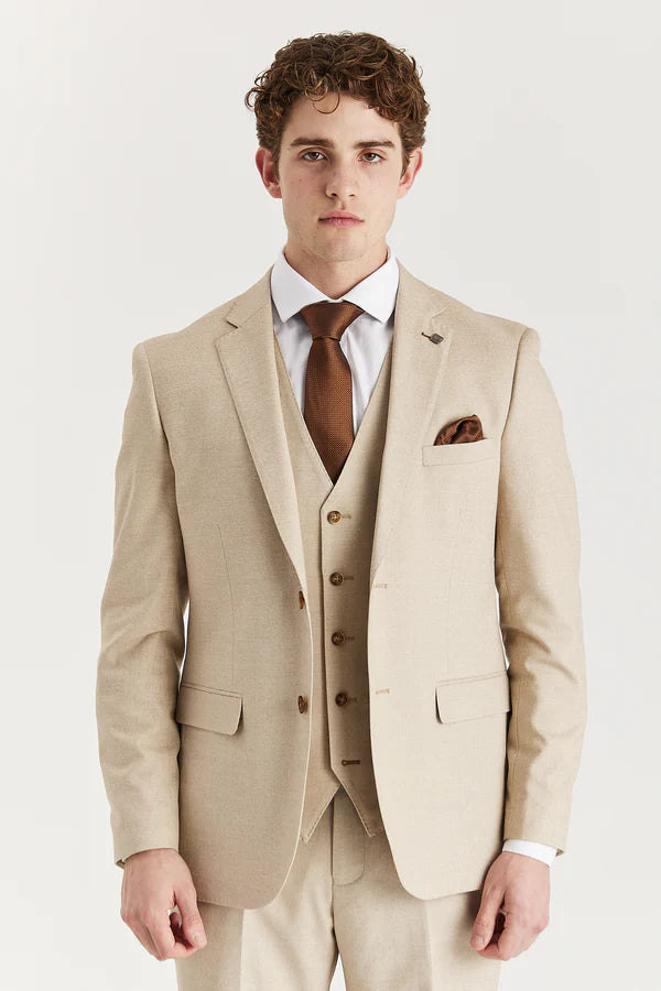 Man wearing a beige suit with a brown tie and pocket square on a white background