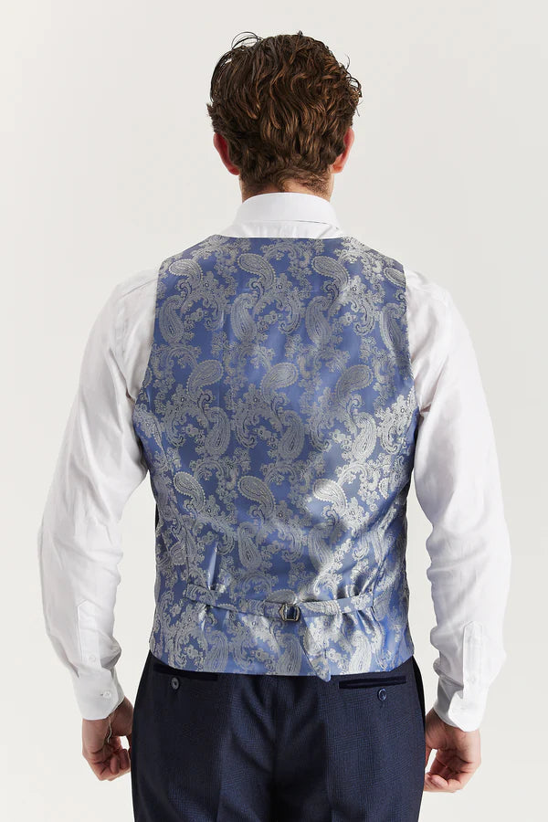 Man wearing a blue paisley patterned vest over a white shirt on a light gray background
