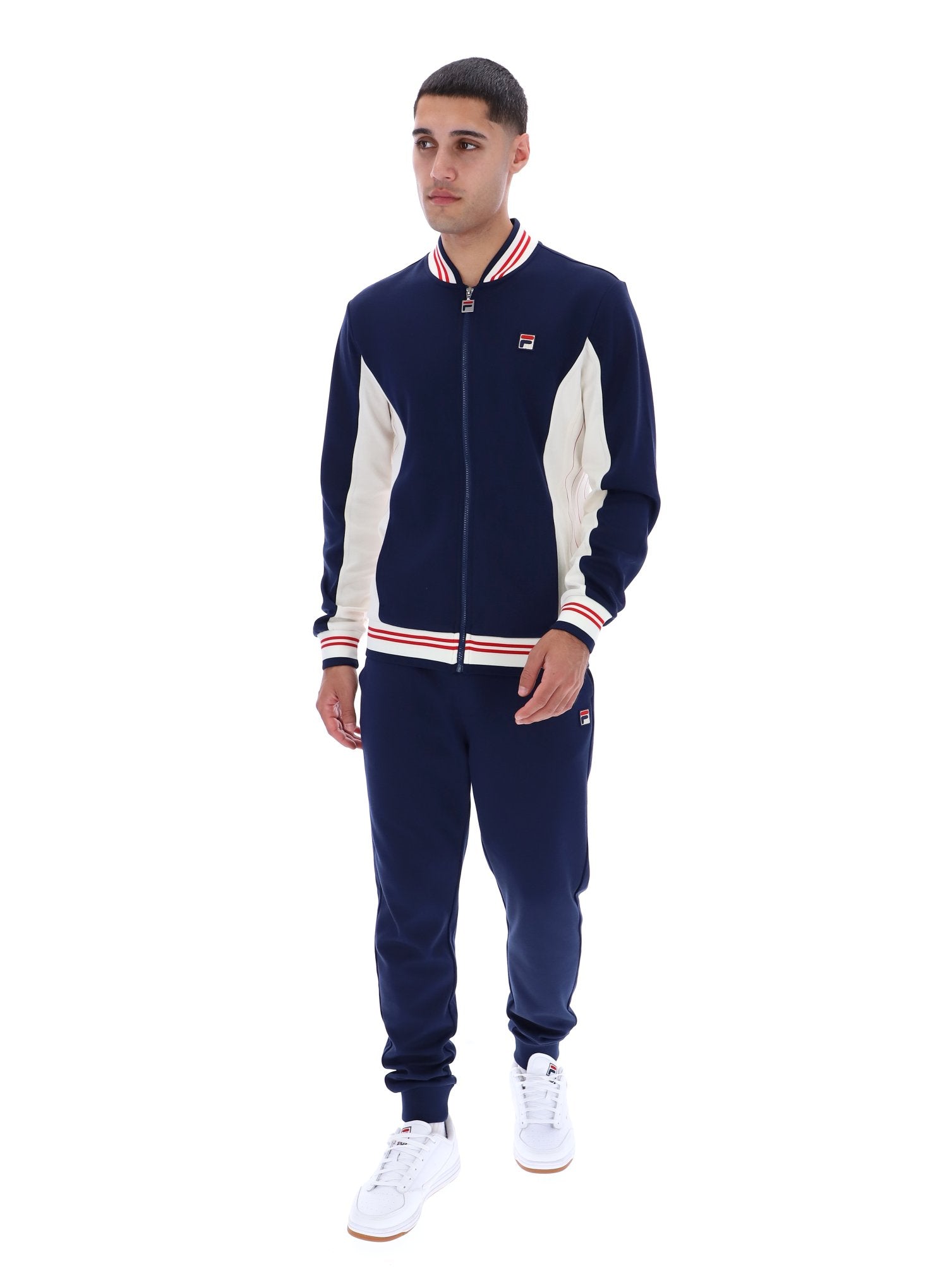 Man wearing a navy and white tracksuit with a visible brand logo on a white background