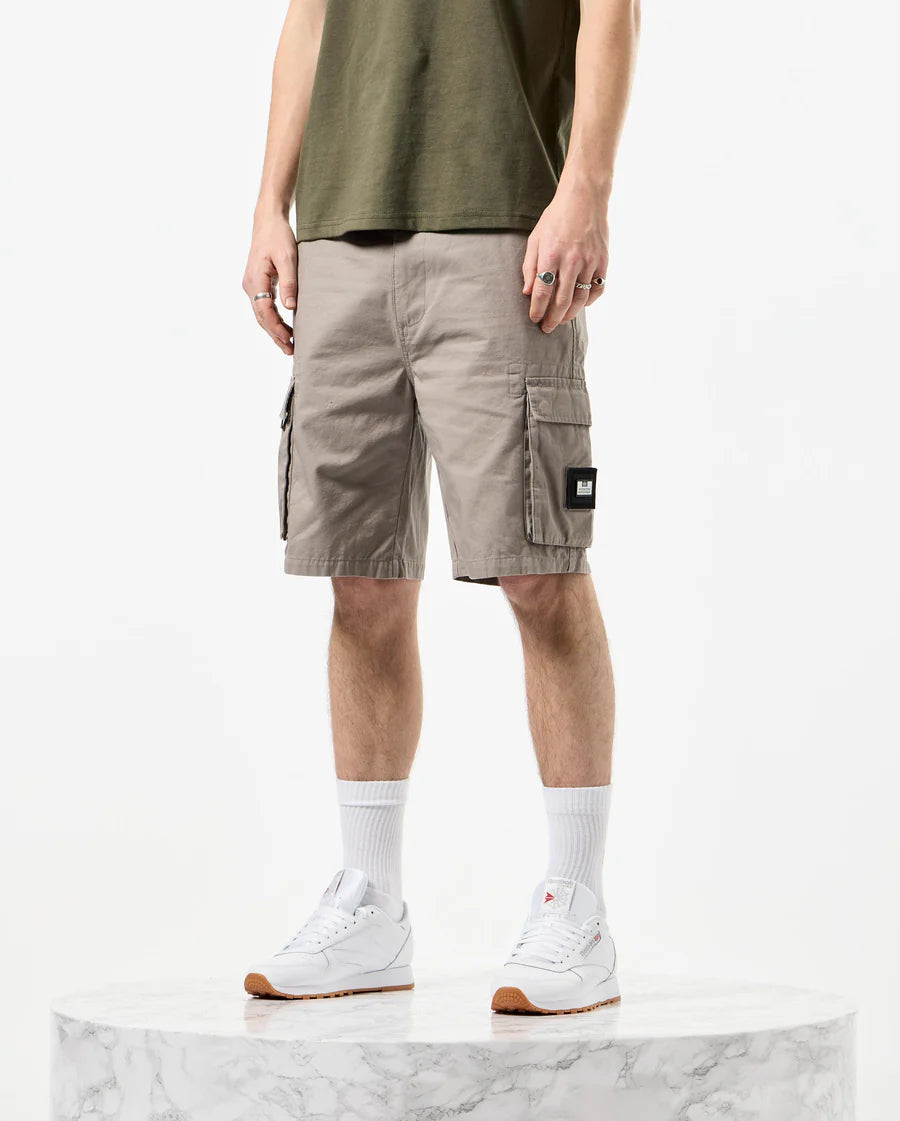 Man wearing green t-shirt and beige shorts on a white background