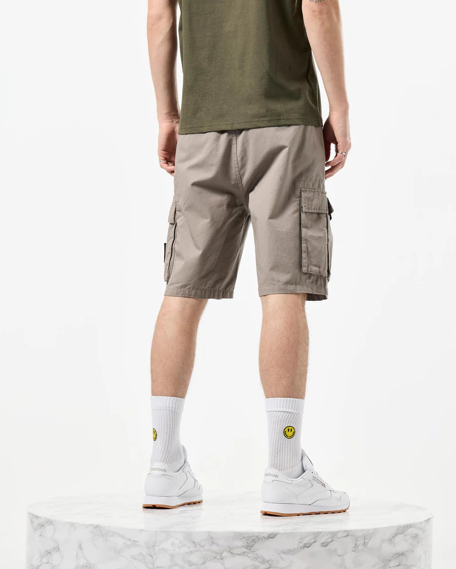 Man wearing green t-shirt and beige shorts on a white background