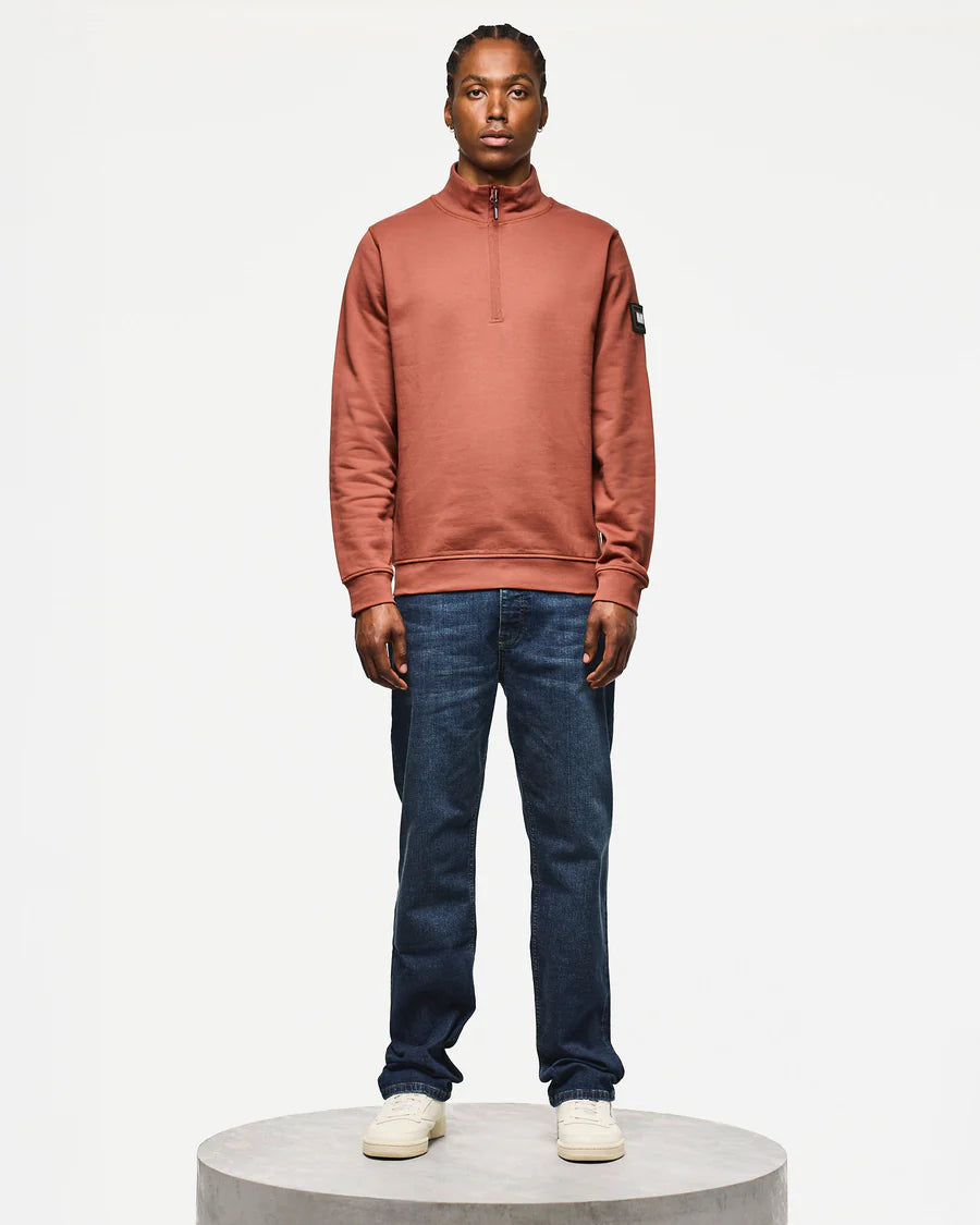 Person wearing a brown sweater and blue jeans on a white background