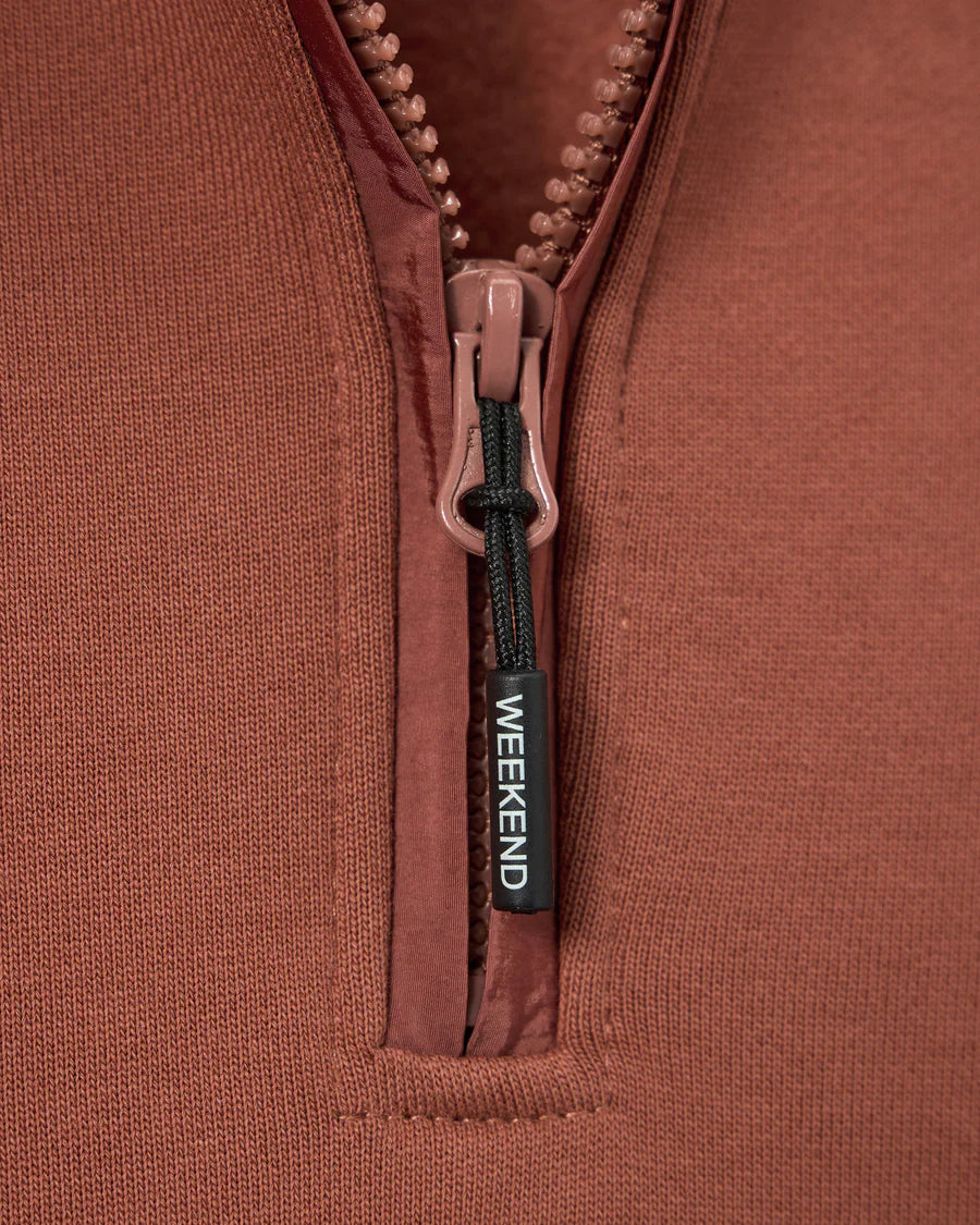 Close-up of a brown jacket zipper with 'Weekend' label