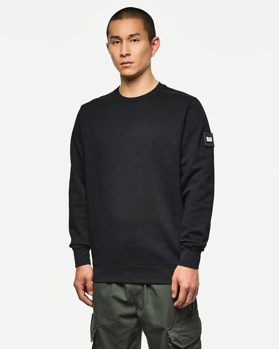 Man wearing a black sweatshirt with a brand logo on a white background