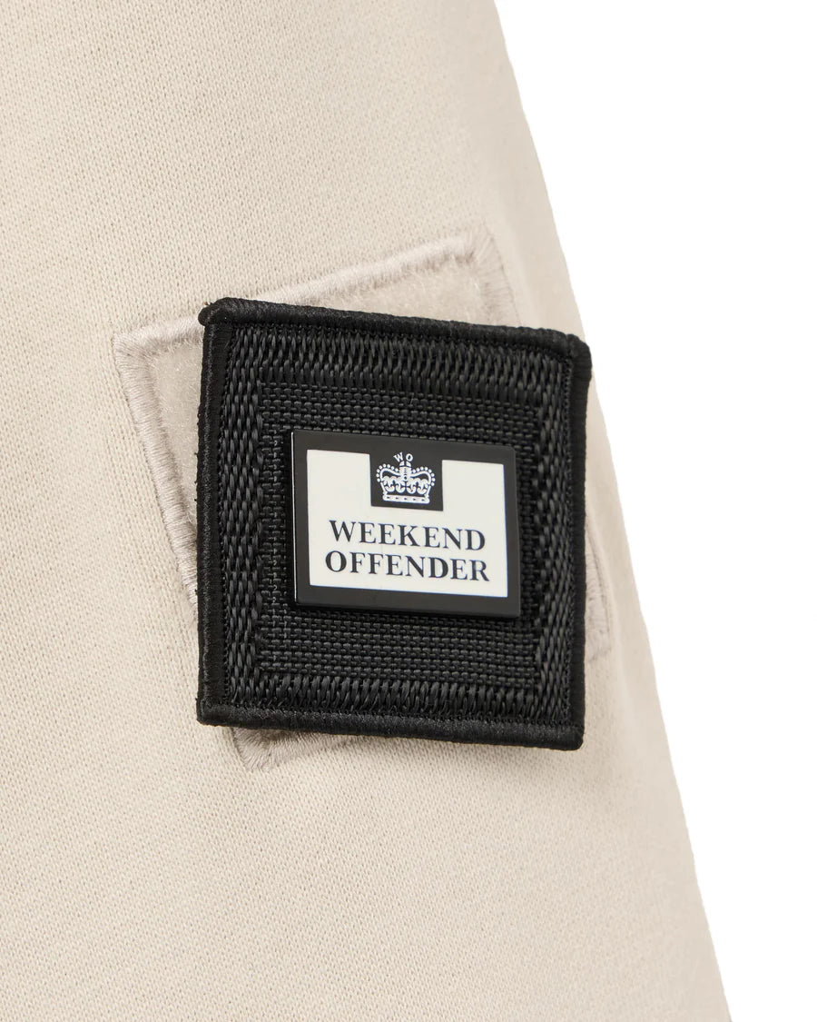 Close-up of a 'Weekend Offender' label on a beige jacket.