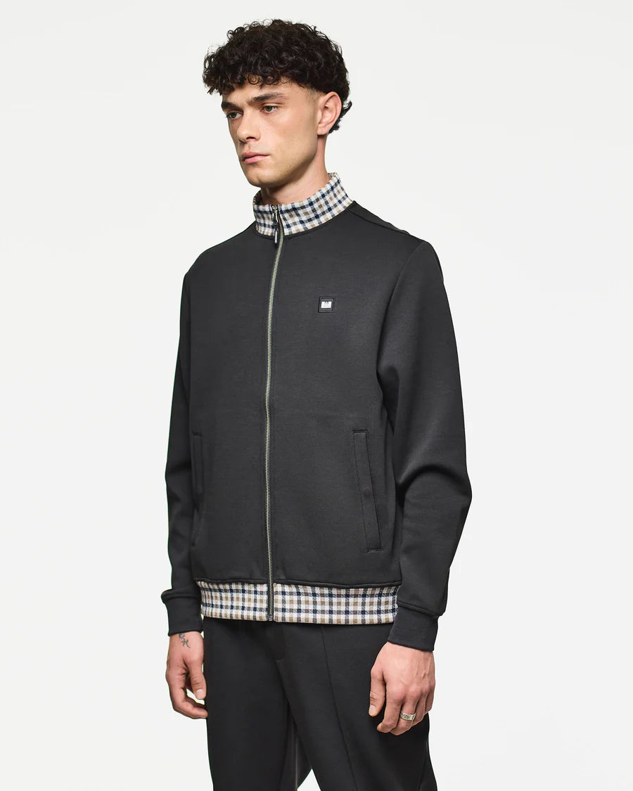 Man wearing a black jacket with a checkered shirt underneath on a white background