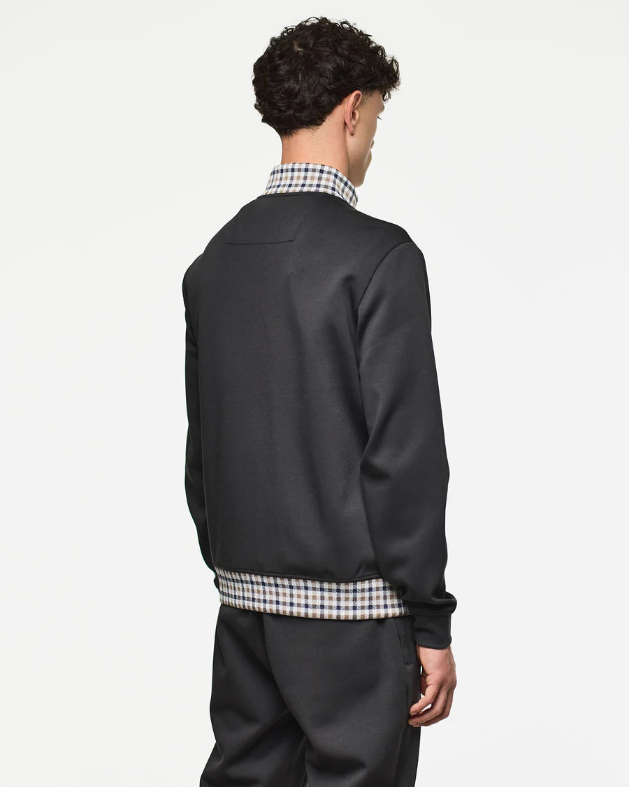 Person wearing a black jacket with plaid accents on a white background