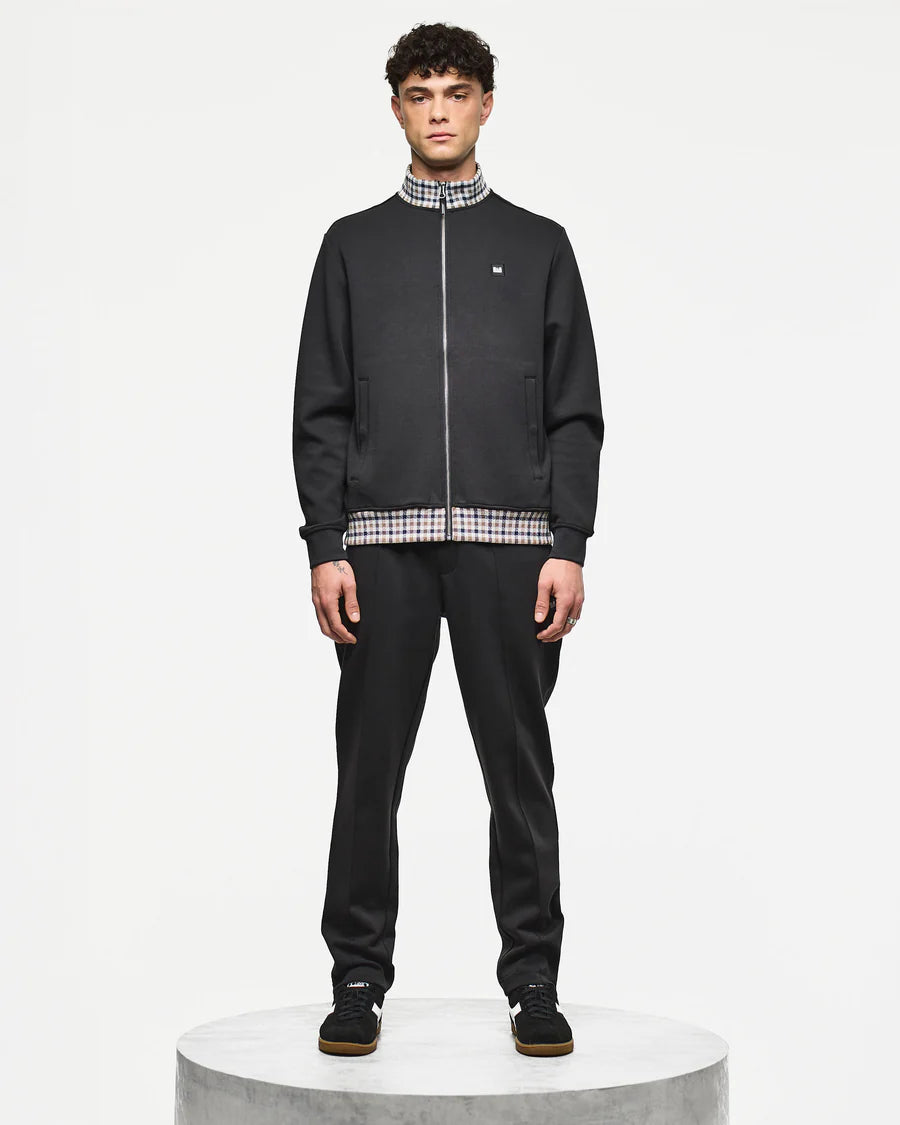 Man wearing a black tracksuit with plaid accents on a white background