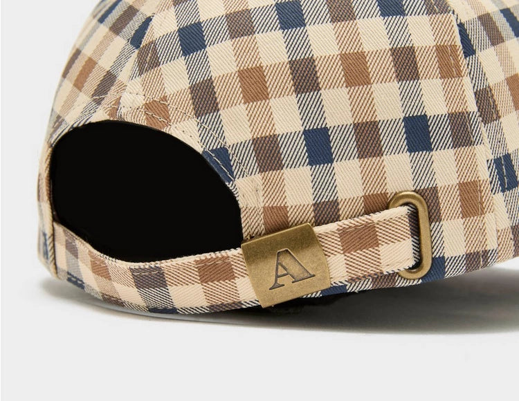 A beige, blue, and brown checkered baseball cap with an adjustable strap and a metal logo emblem on the back.