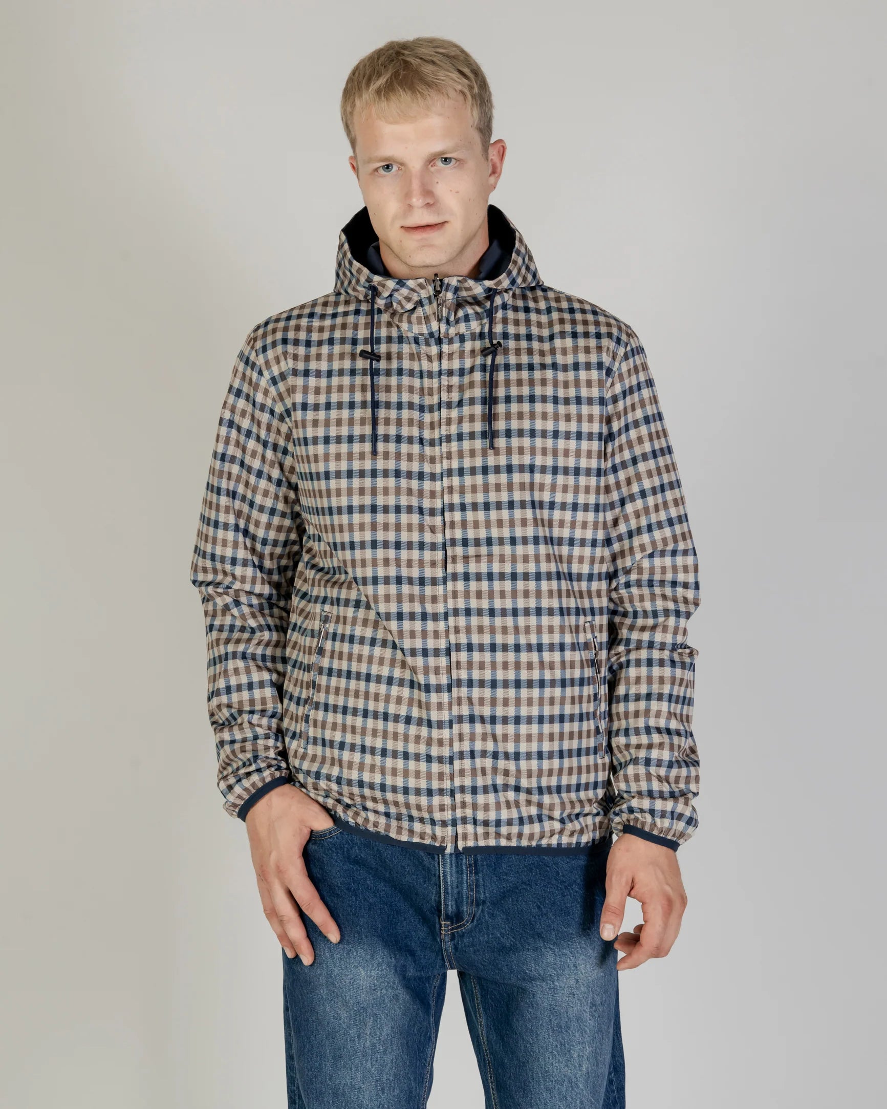 A reversible jacket with the outer side in navy color and the inner side in a club check pattern. The jacket features a hood, pockets, and a full zip closure.