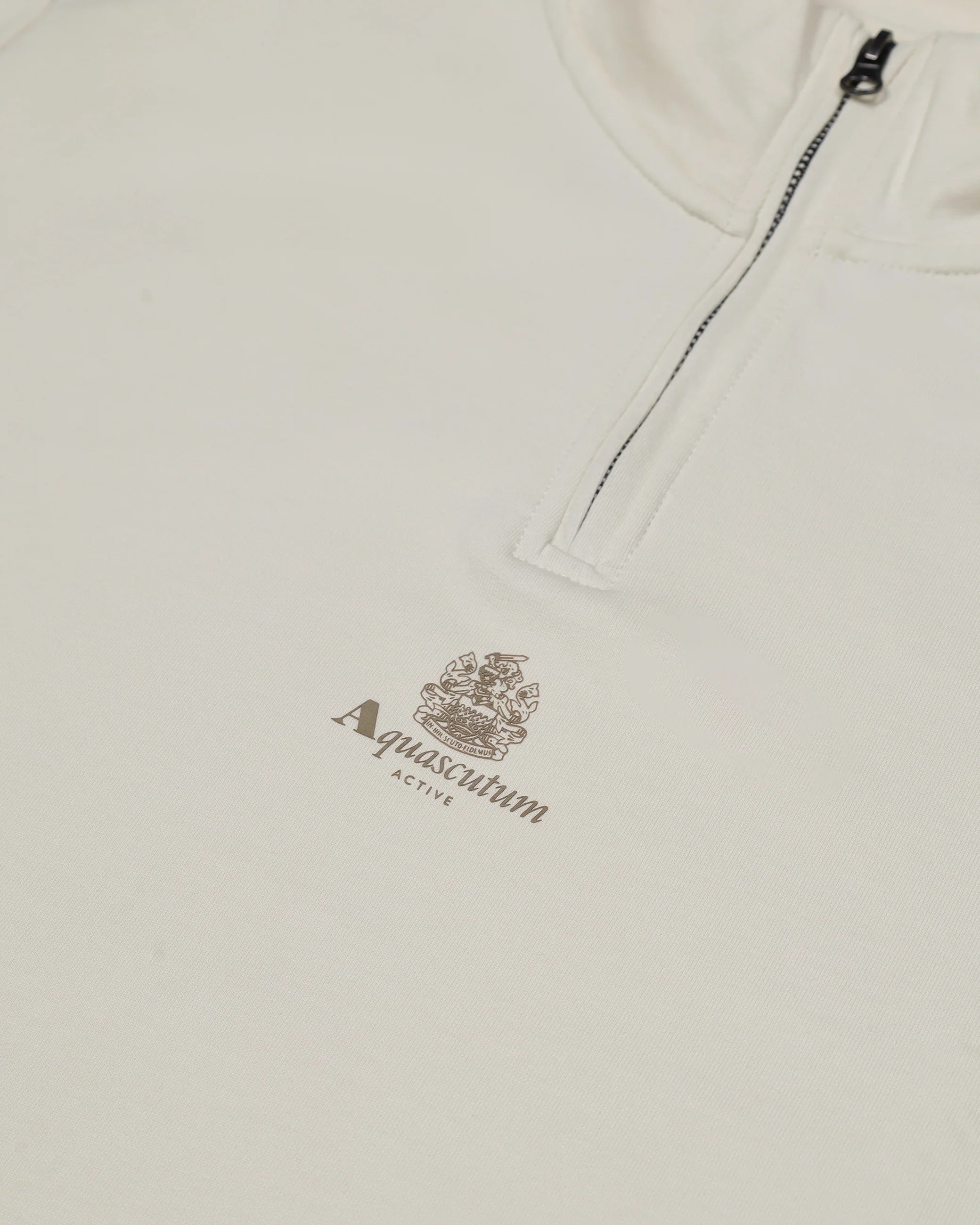 Close-up of a beige fleece with Aquascutum logo and text on a white background