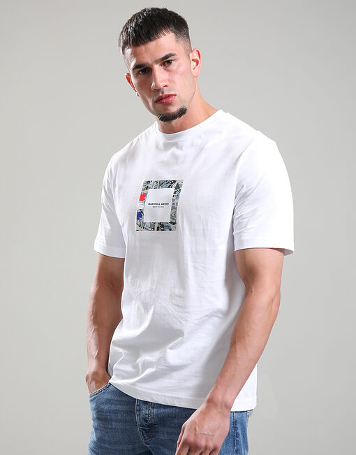 Man wearing a white t-shirt with a graphic design on a plain background