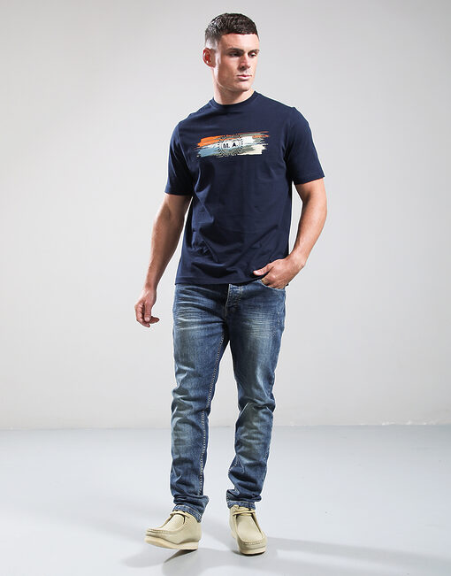 Man wearing a navy t-shirt with a graphic design and blue jeans on a white background