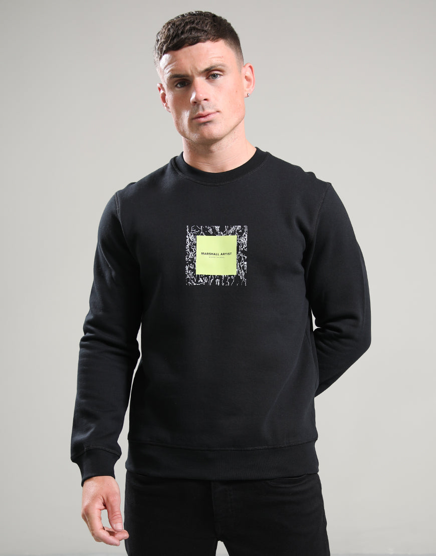 Man wearing a black sweatshirt with a yellow square design on a gray background