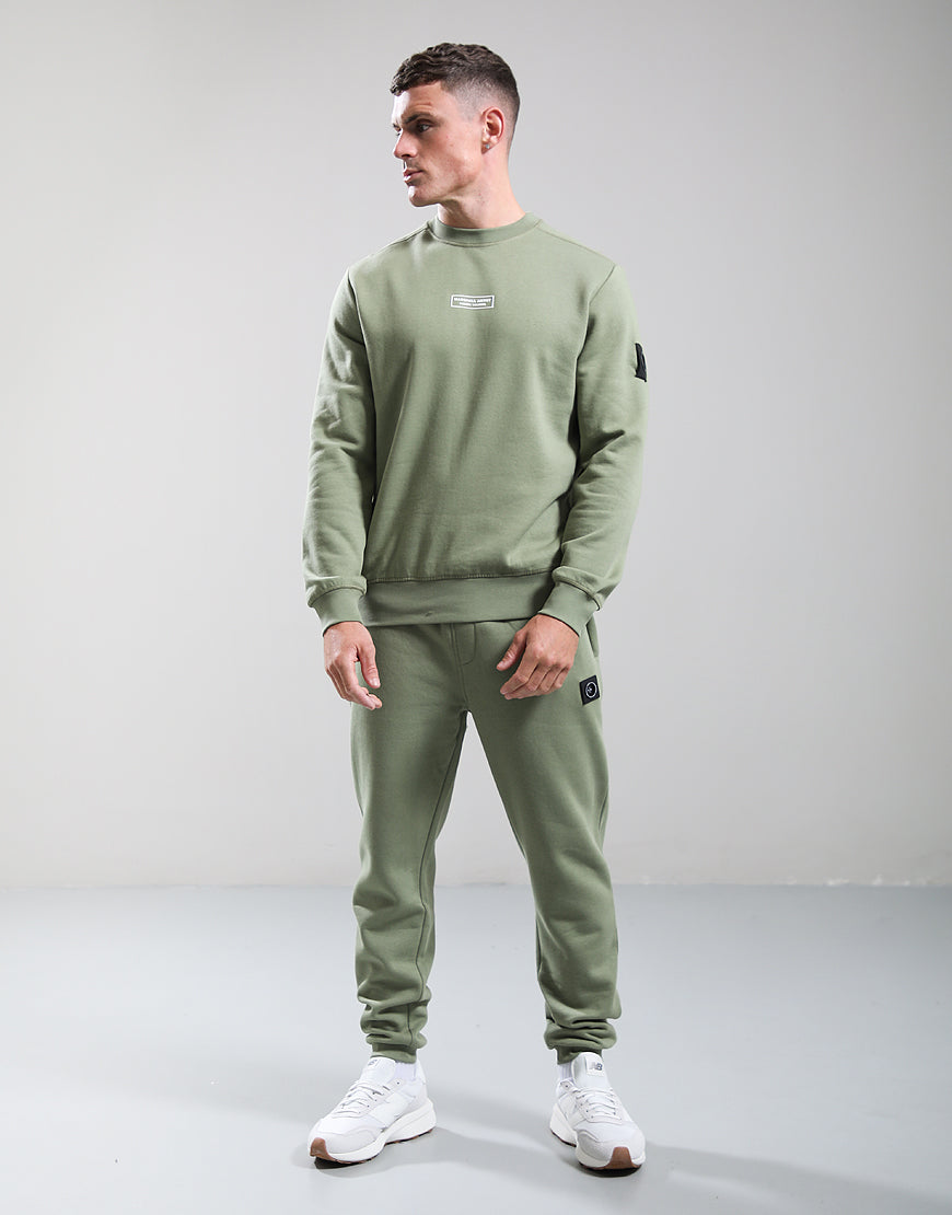 Man wearing a green tracksuit with white sneakers on a plain background