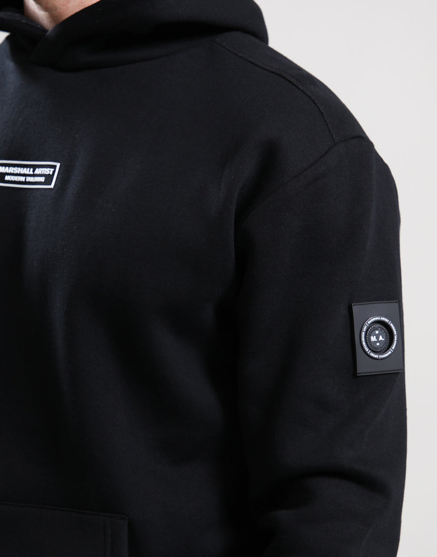 Black hoodie with brand logo on sleeve against a light gray background