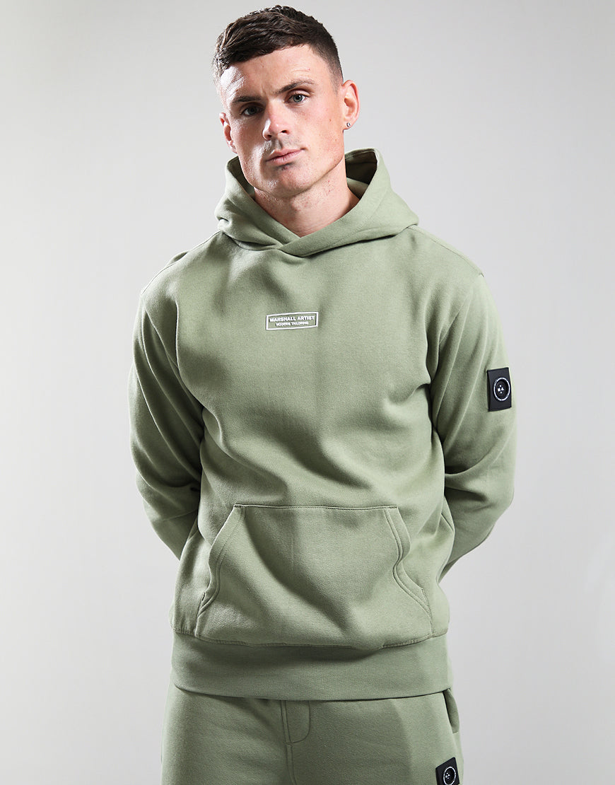 Man wearing a green hoodie with brand logos on a light gray background