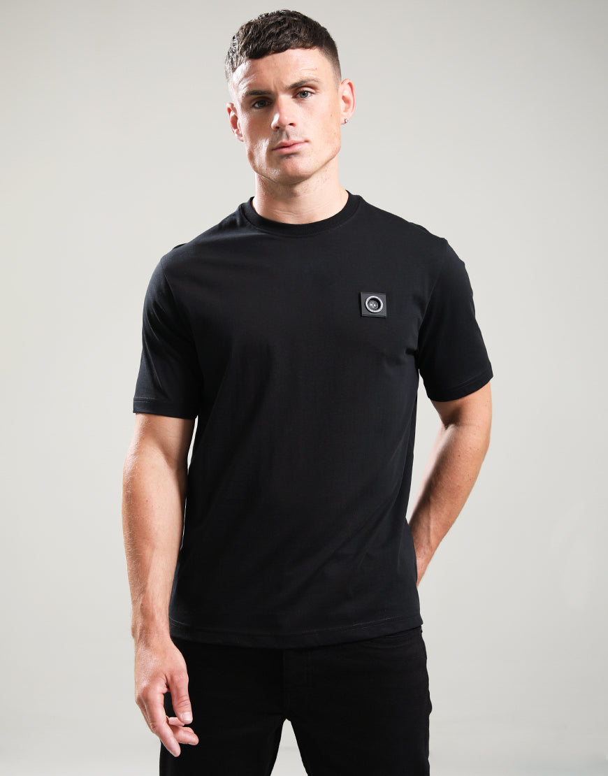 Man wearing a black t-shirt with a small logo on a gray background