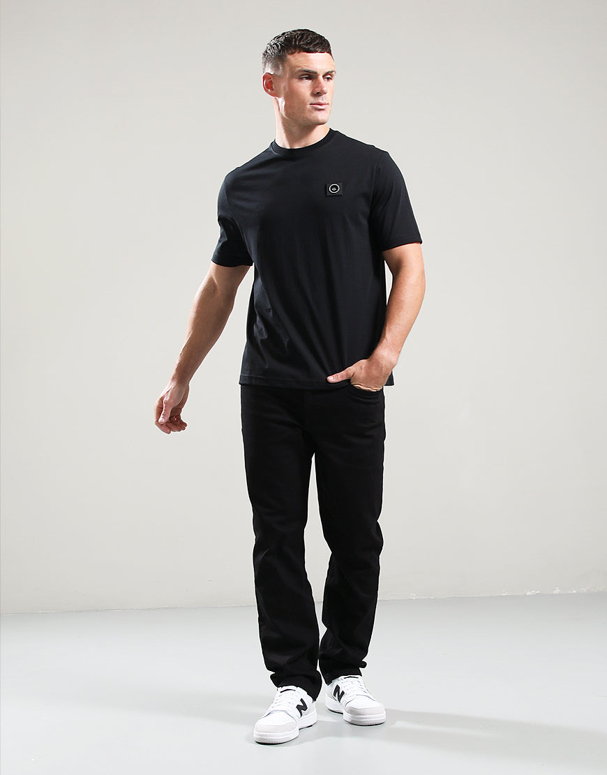 Man wearing a black t-shirt and pants with white sneakers on a light gray background