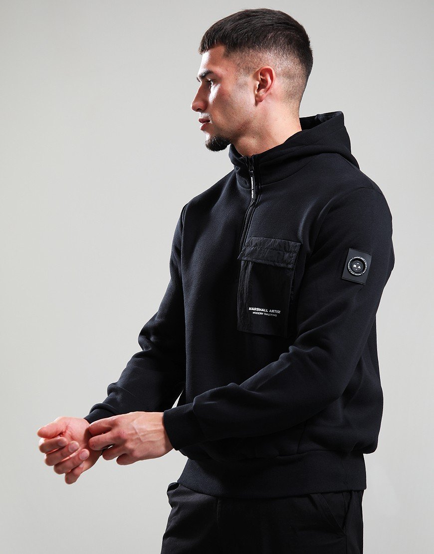 Man wearing a black hoodie with a brand logo on a gray background