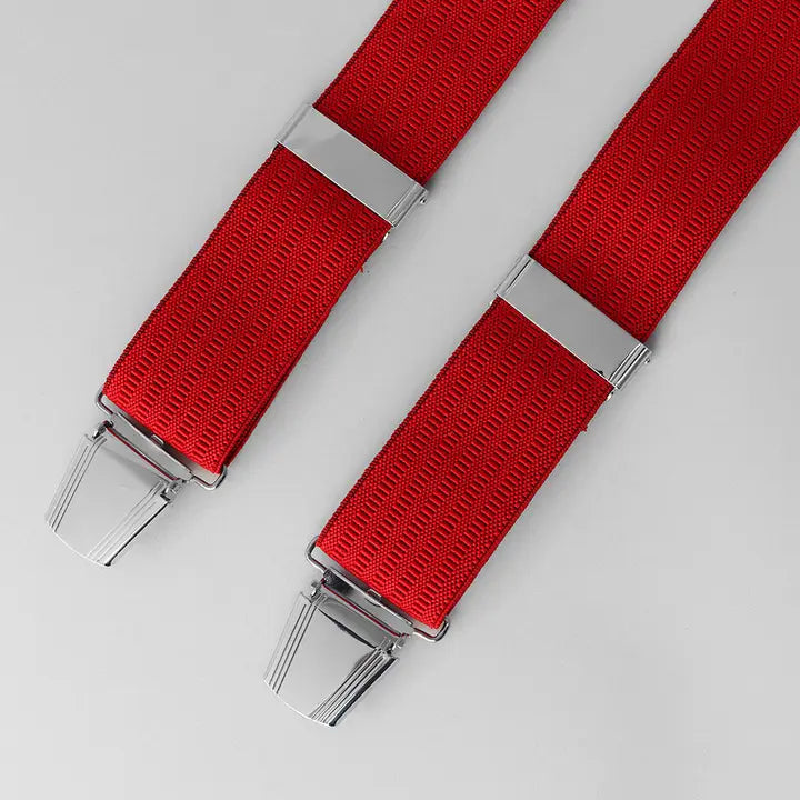 Red suspenders with silver clips on a light gray background