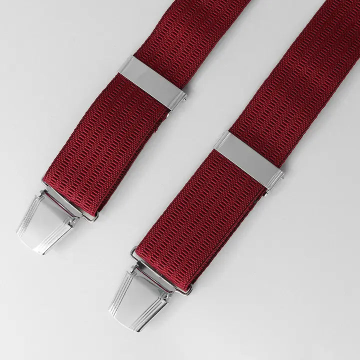 Two red suspenders with silver clips on a light gray background