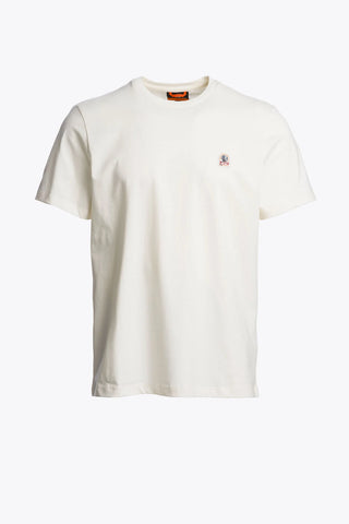 An off-white short-sleeve crewneck t-shirt with a small embroidered logo on the left chest, displayed against a solid light gray background.
