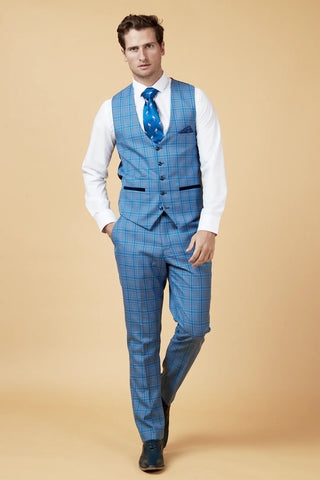 Man wearing a blue checkered suit with a white shirt and blue tie on a beige background