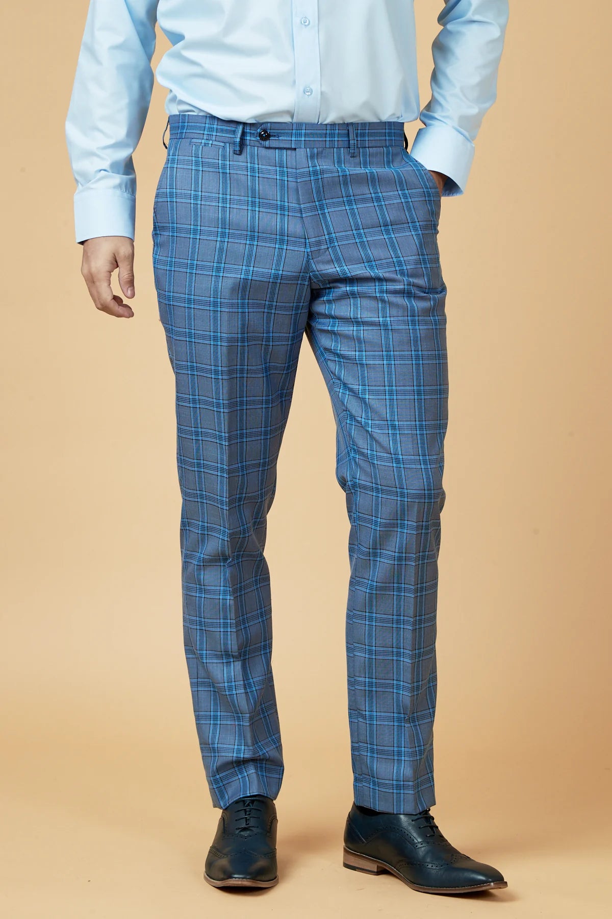 Person wearing blue checkered pants and a light blue shirt on a beige background