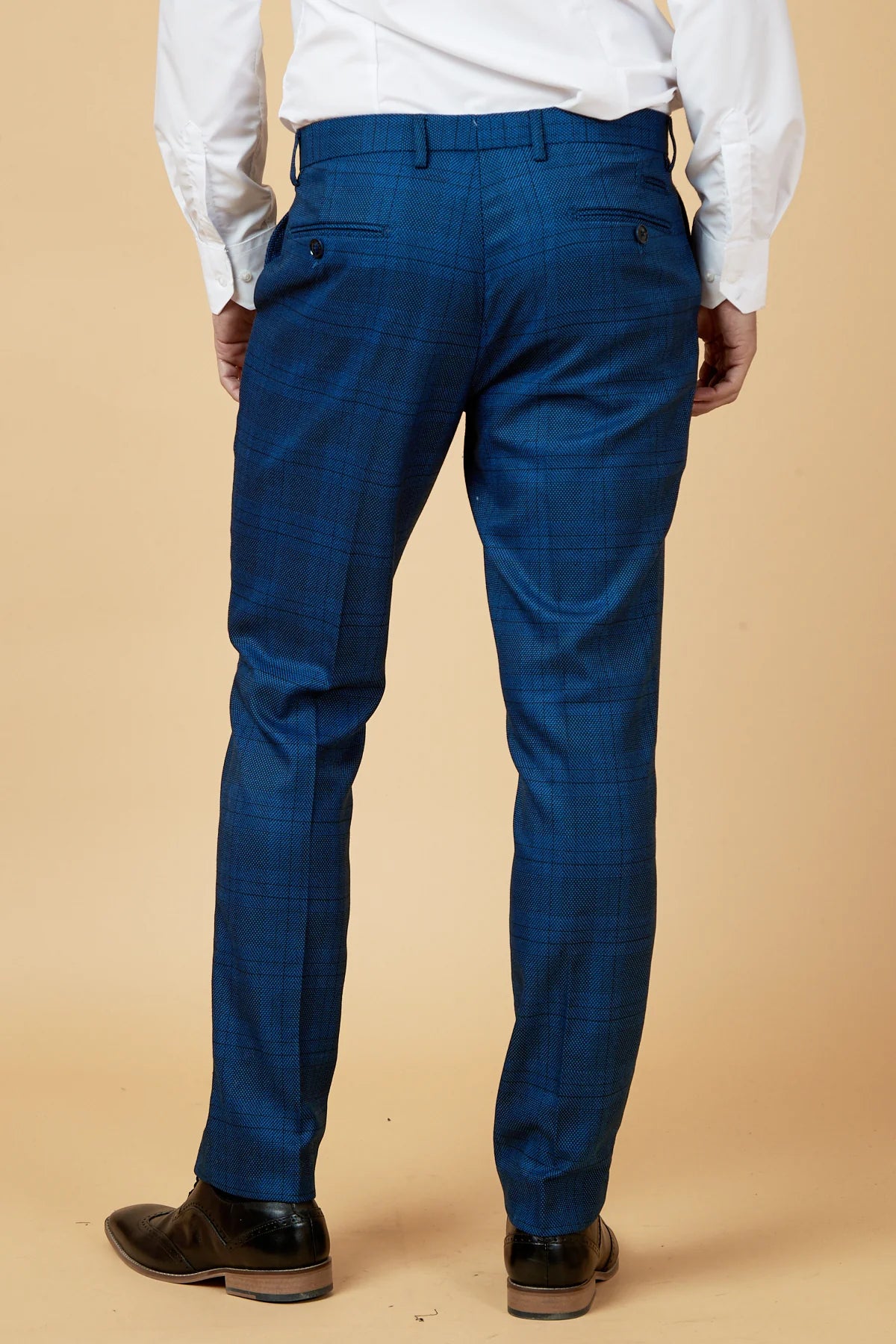 Person wearing blue pants and a white shirt against a beige background