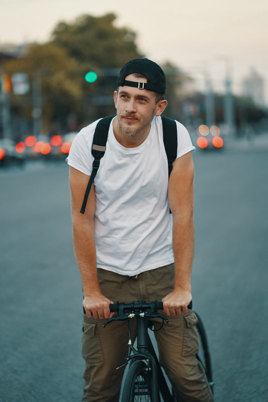 Man with a backpack standing next to a bicycle on a street.