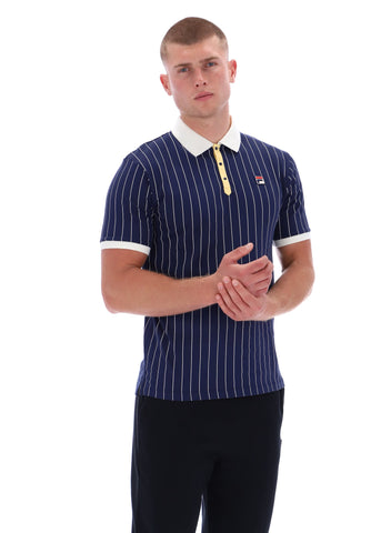 Man wearing a navy pinstripe polo shirt with white collar and cuffs on a white background