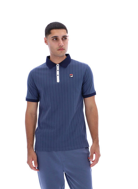 Man wearing a blue ribbed polo shirt with a collar and a small logo on a white background