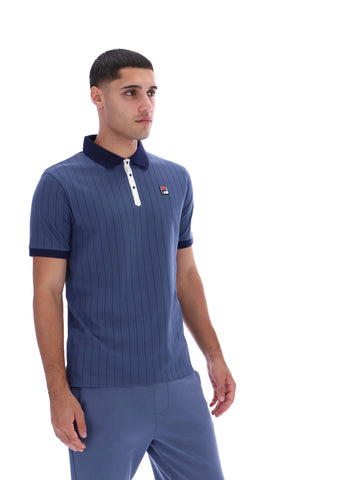 Man wearing a blue ribbed polo shirt with a small logo on a white background