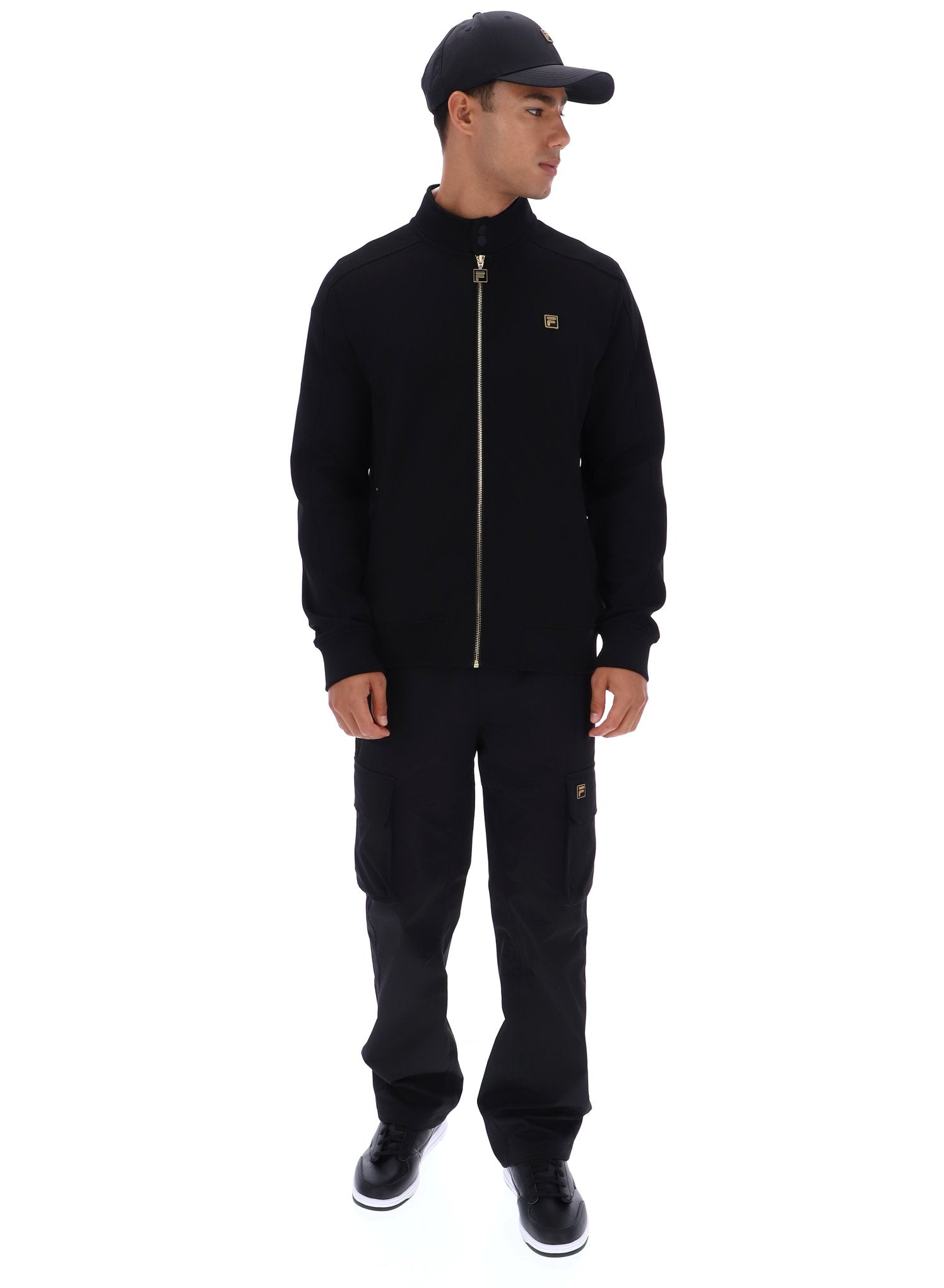 Person wearing a black jacket and pants with a cap on a white background