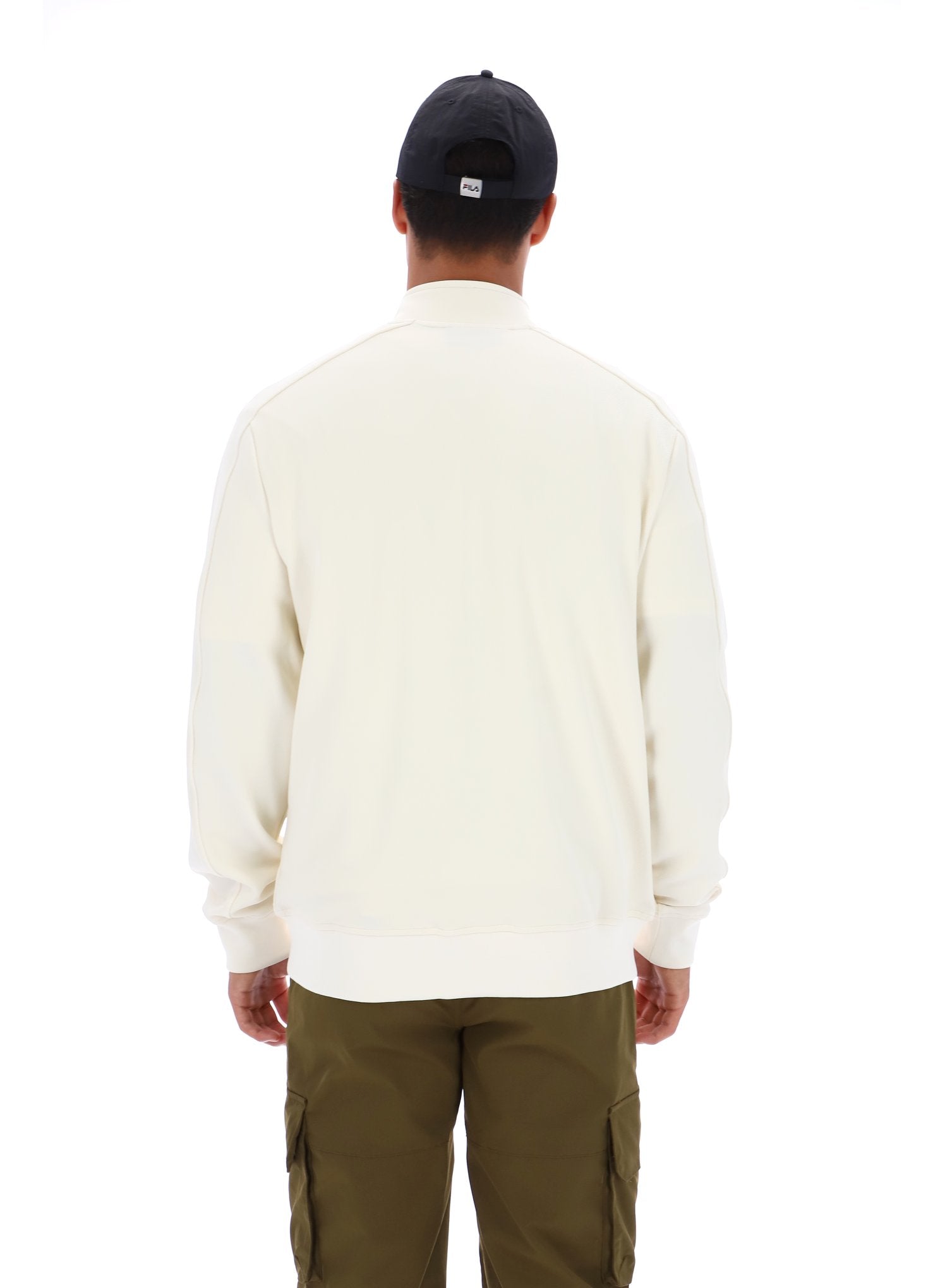 Person wearing a white sweater and green pants with a black cap on a white background