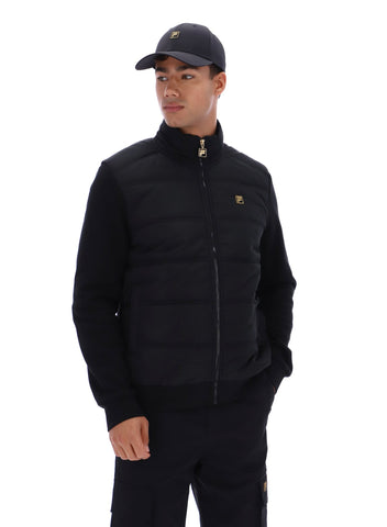 Man wearing a black jacket and cap with brand logos on a white background