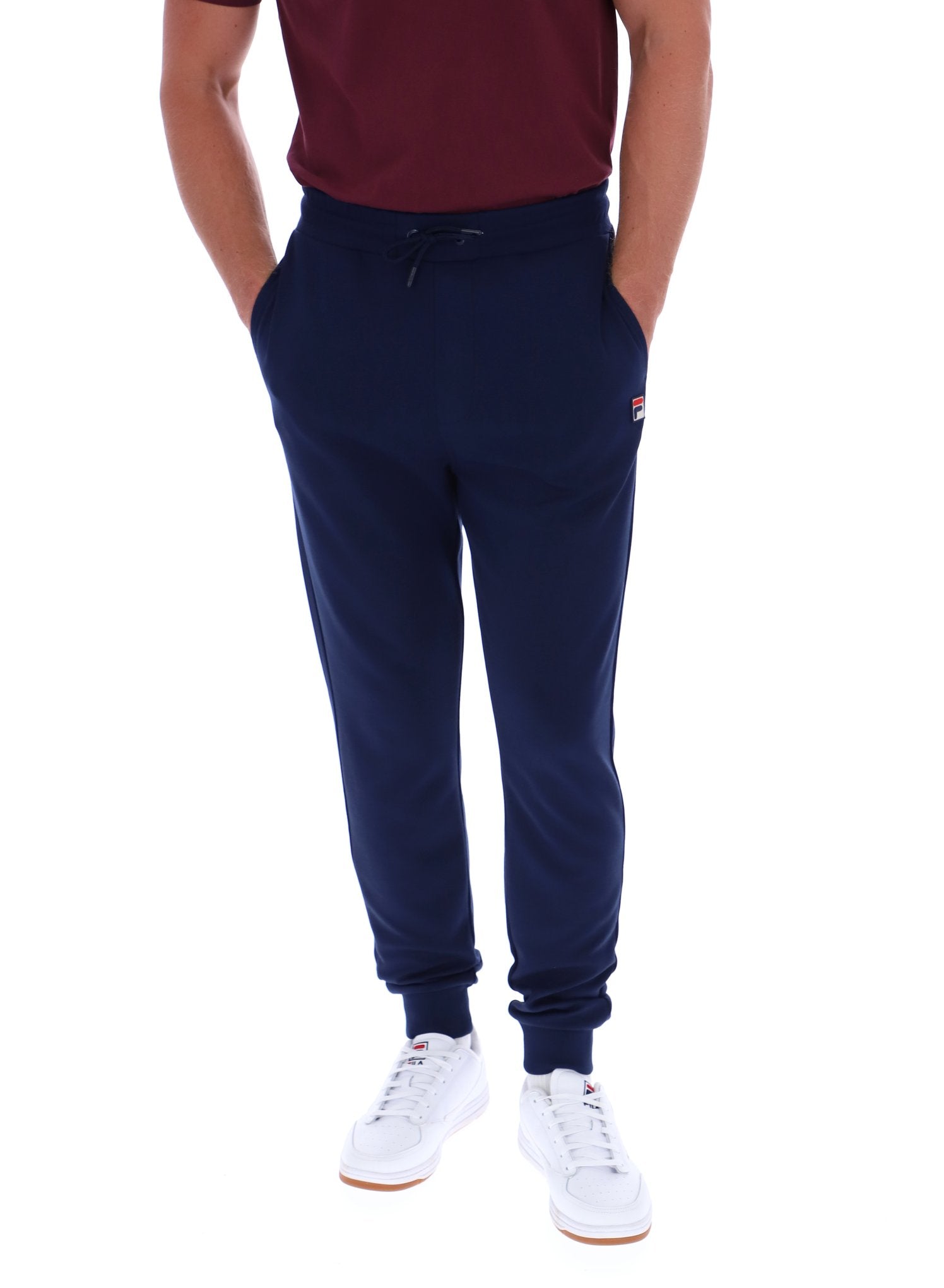 Person wearing navy jogger pants with a brand logo on a white background
