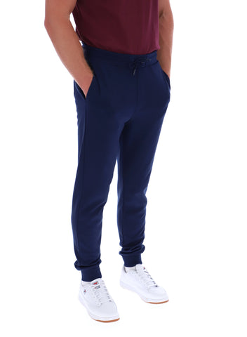 Person wearing navy jogger pants and white sneakers on a white background