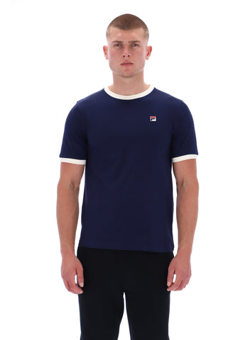 Man wearing a navy blue t-shirt with a small logo on a white background