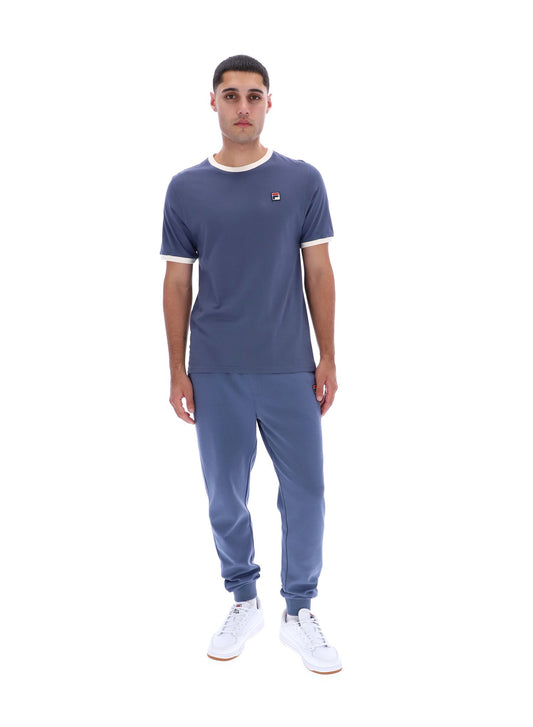 Man wearing a blue t-shirt and pants with a logo on a white background