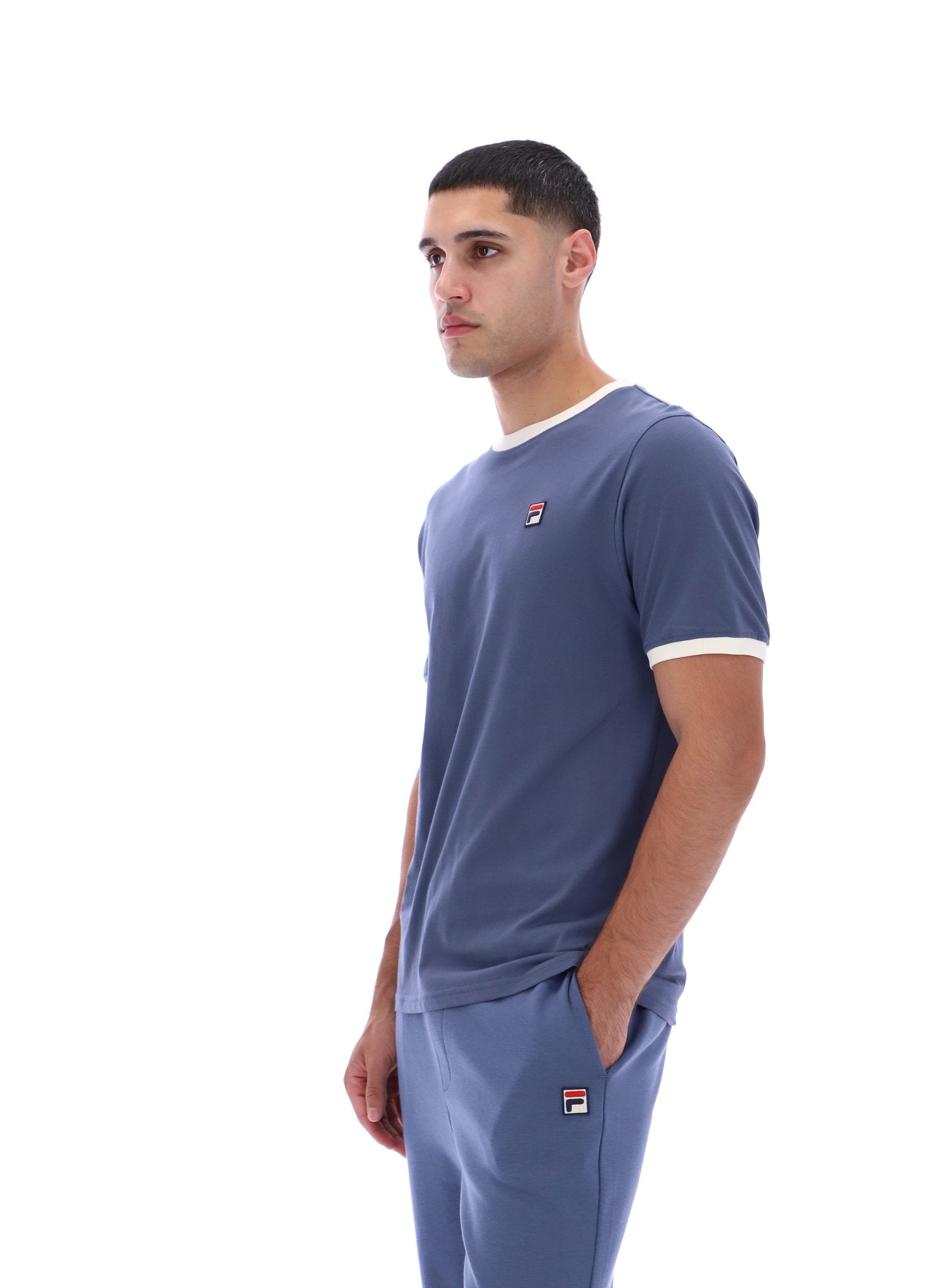 Man wearing a blue t-shirt and pants with a logo on a white background