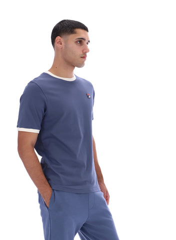 Man wearing a blue t-shirt and pants with a small logo on a white background