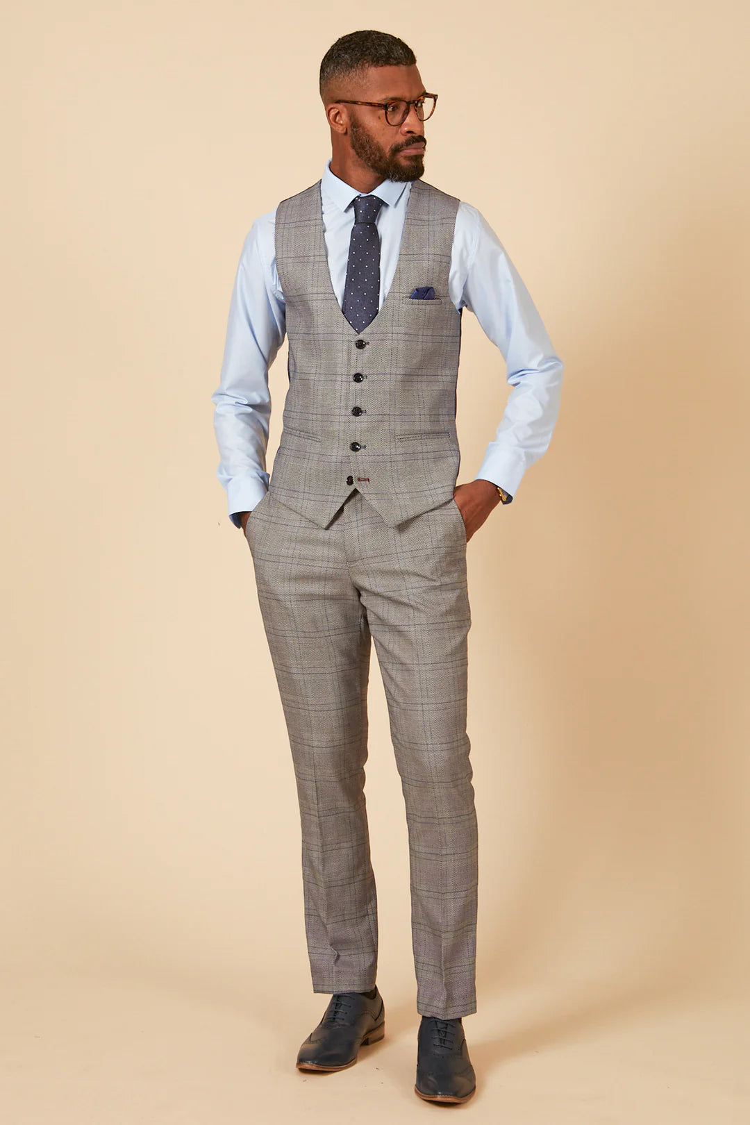 Man wearing a gray checkered vest and pants on a beige background